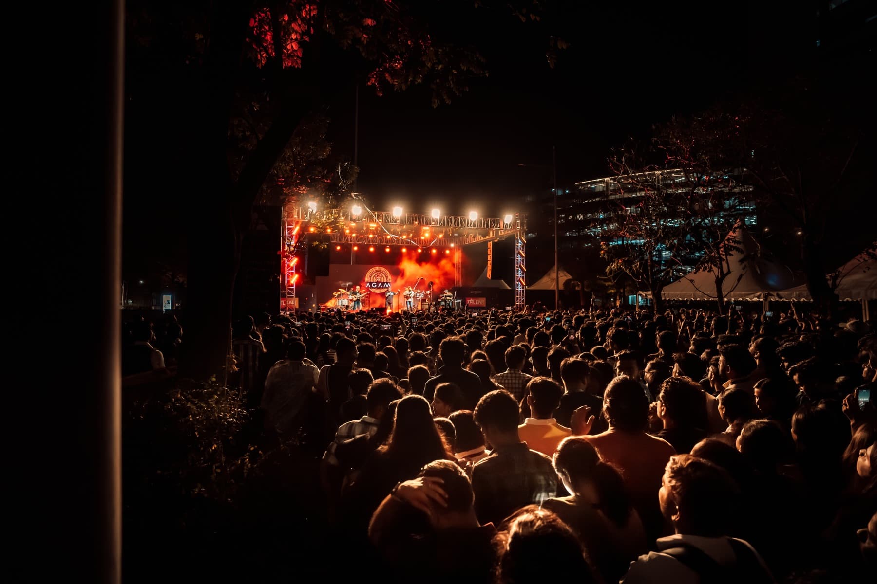 Agam performing outdoors at night before a dense crowd