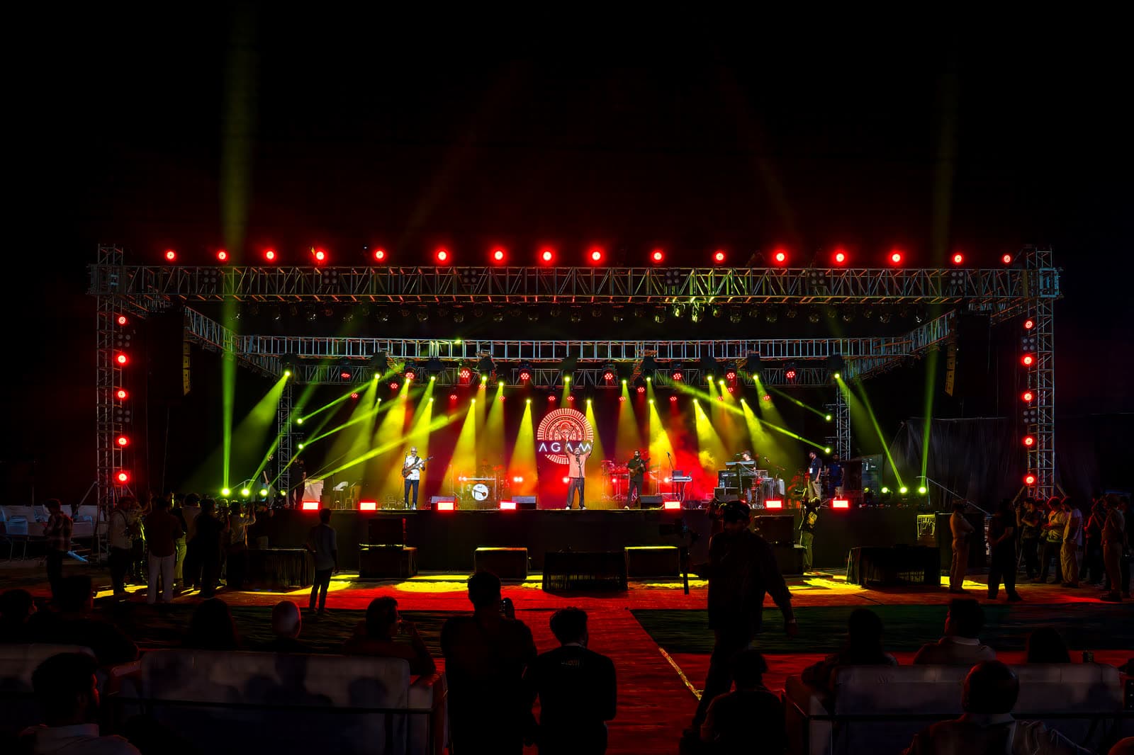 Agam performing live on a large stage with red and yellow lights